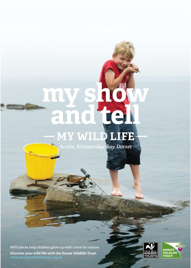 an excited young boy on a rock in a lake holding a crab with the caption, "my show and tell."